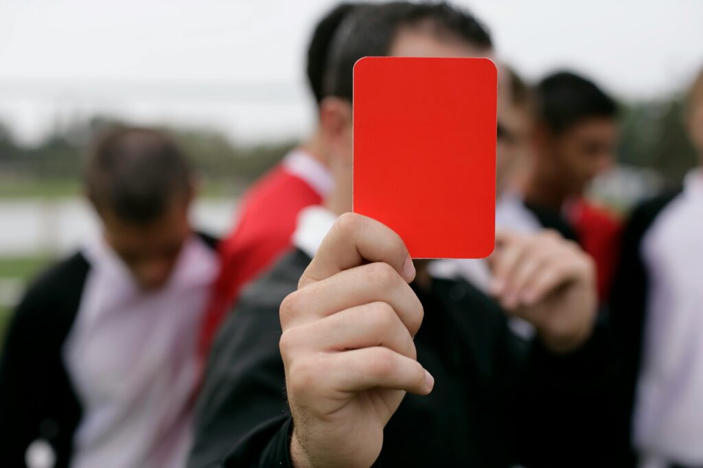 pexels-photo-12585892-12585892 Referee showing a red card to players during an outdoor soccer game.