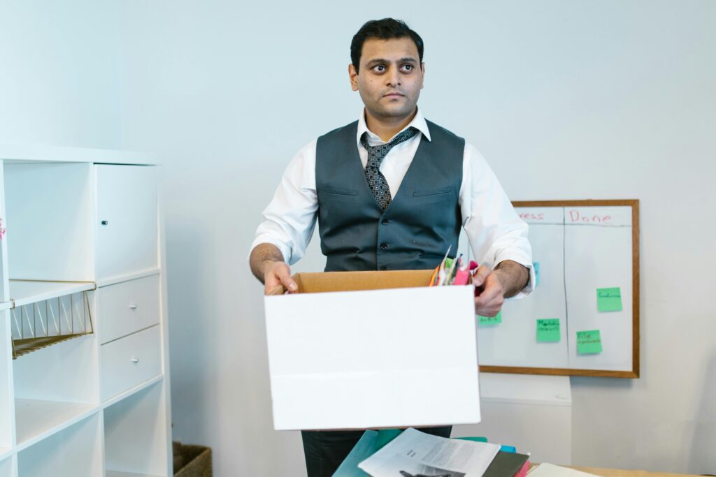 pexels-photo-7581040-7581040 Professional man organizing office belongings in a cardboard box, preparing for transition.